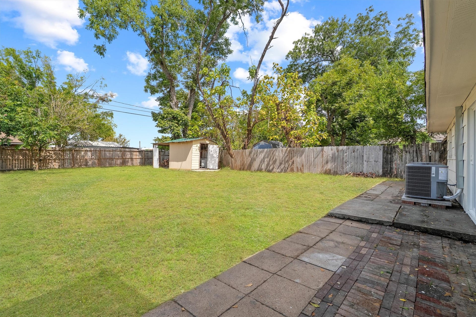 6630 Maybank Drive, Houston, TX 77055 Spacious backyard with a well-maintained lawn, a convenient storage shed, and a paved patio area perfect for outdoor activities and relaxation.