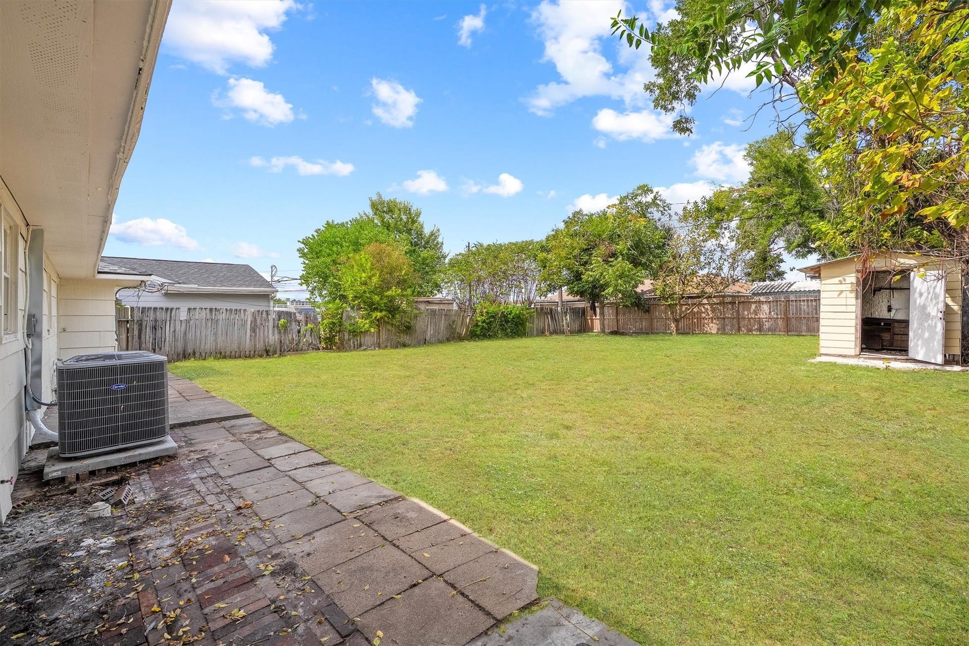 6630 Maybank Drive, Houston, TX 77055 Expansive backyard with lush green grass, a spacious patio area, and a convenient storage shed, perfect for outdoor activities and gatherings.