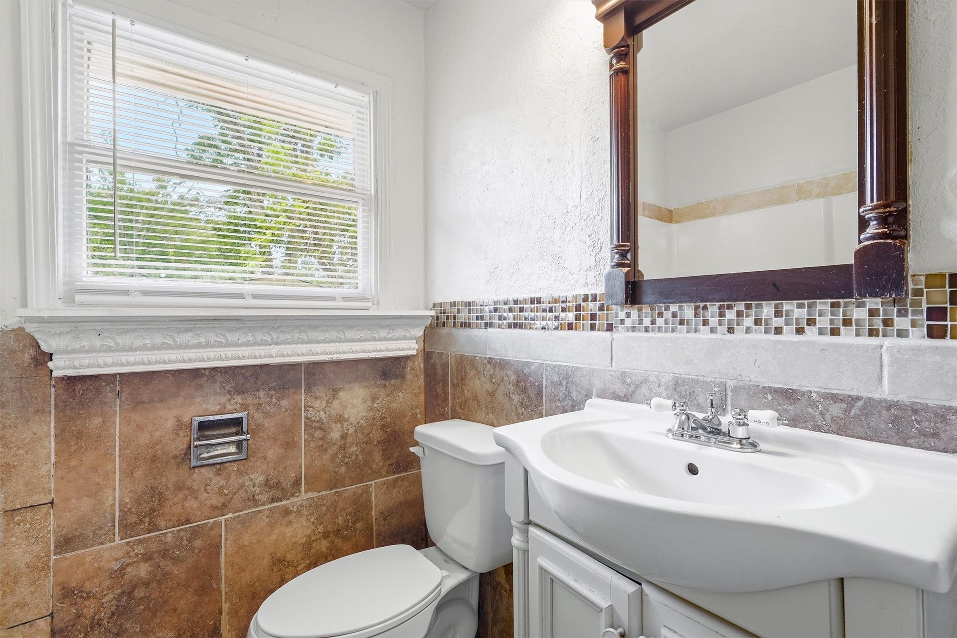 6630 Maybank Drive, Houston, TX 77055 Charming bathroom featuring elegant tile work, a classic vanity with a decorative mirror, and a bright window that fills the space with natural light.