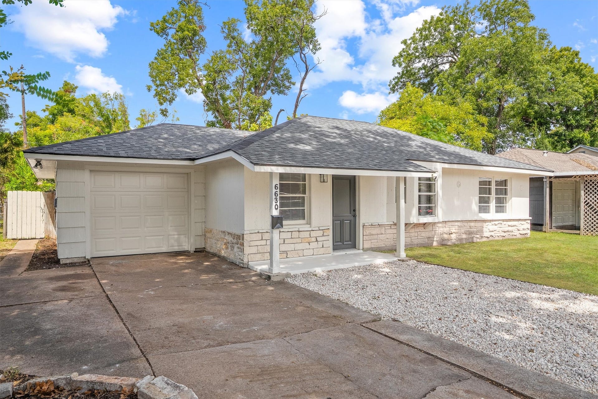 6630 Maybank Drive, Houston, TX 77055 Charming single-story home featuring a clean, modern facade with stone accents, a spacious driveway, and a lush green lawn, perfect for easy living.