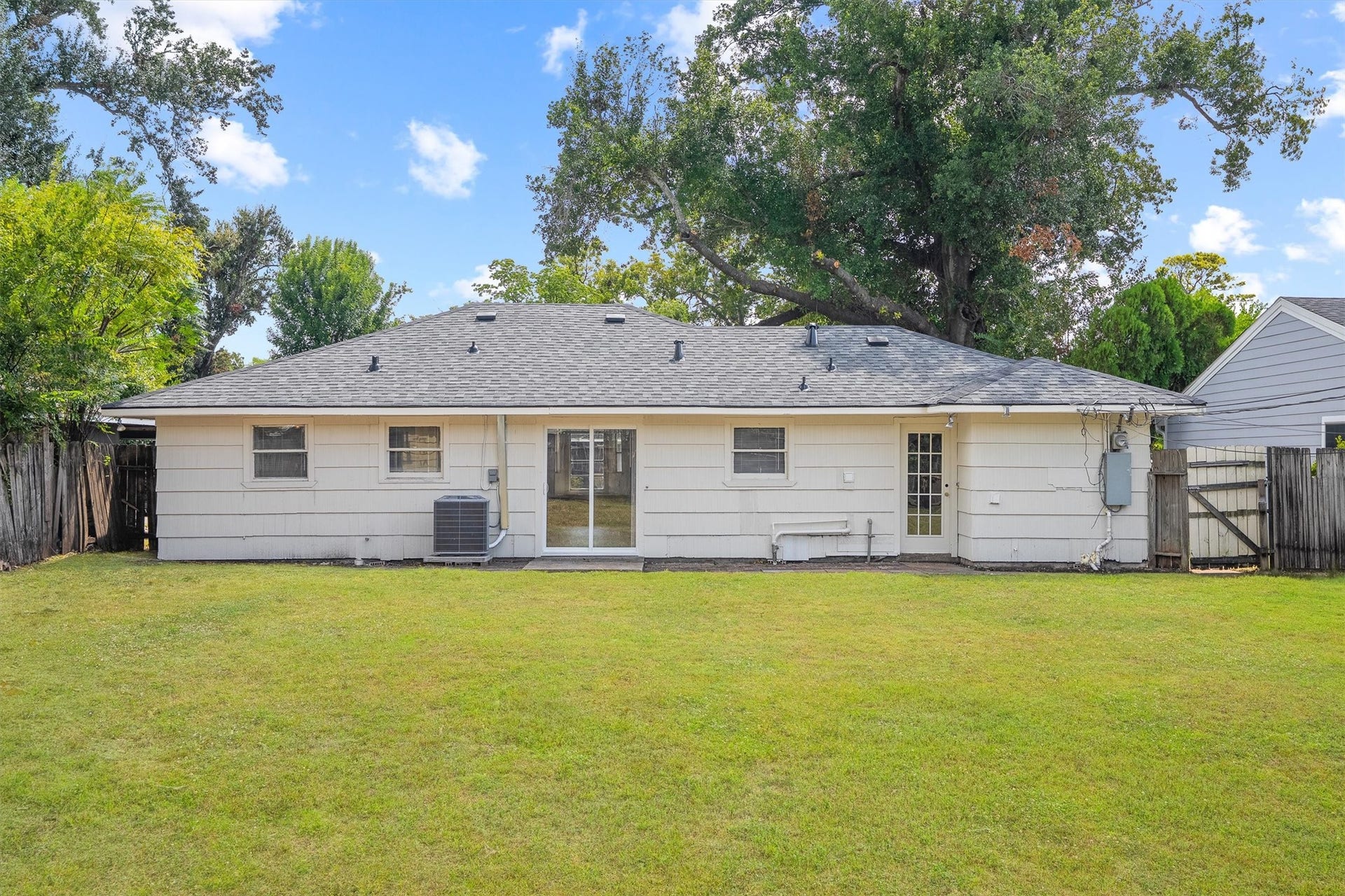 6630 Maybank Drive, Houston, TX 77055 Charming single-story home with a spacious backyard, perfect for outdoor activities. The exterior features a sturdy roof and convenient patio access, surrounded by mature trees for added privacy.