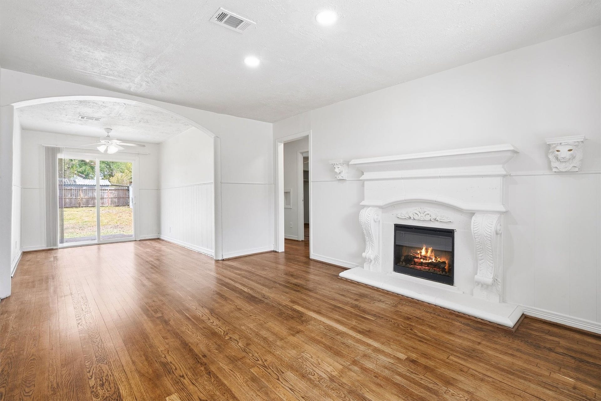 6630 Maybank Drive, Houston, TX 77055 Elegant living space featuring a stunning white fireplace, rich hardwood floors, and ample natural light streaming through sliding glass doors leading to the backyard.