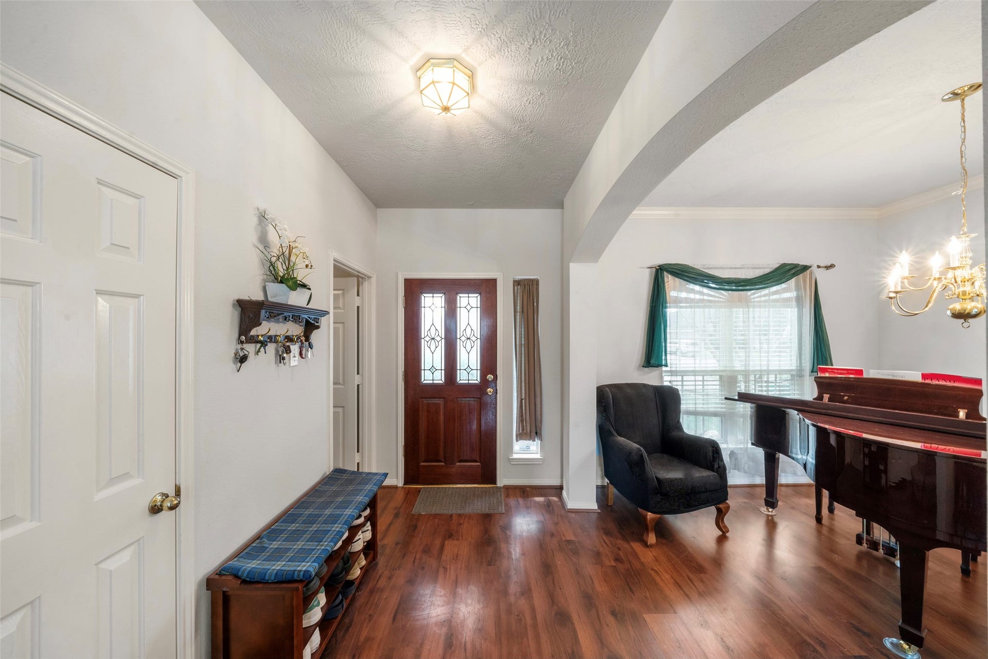 3607 Parkshire Drive, Pearland, TX 77584 Inviting entryway with elegant flooring, leading to a cozy seating area and a sophisticated piano room/dining room, enhanced by natural light and a warm chandelier.