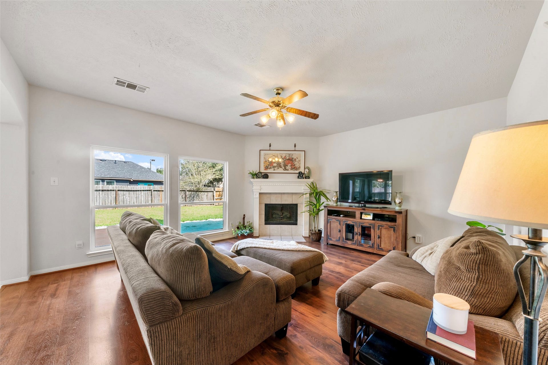 3607 Parkshire Drive, Pearland, TX 77584 Inviting living room with warm flooring, a cozy fireplace, and abundant natural light from large windows overlooking the backyard.