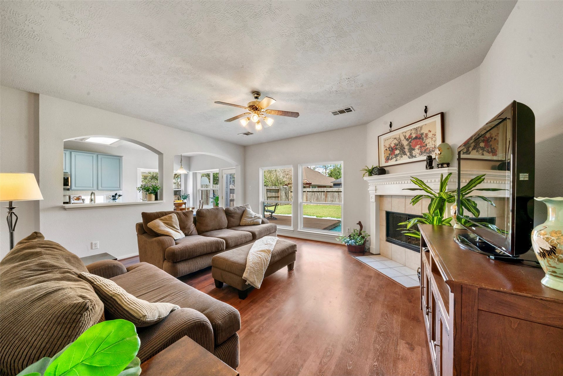3607 Parkshire Drive, Pearland, TX 77584 Spacious living room featuring warm flooring, a cozy fireplace, and abundant natural light from large windows overlooking the backyard.
