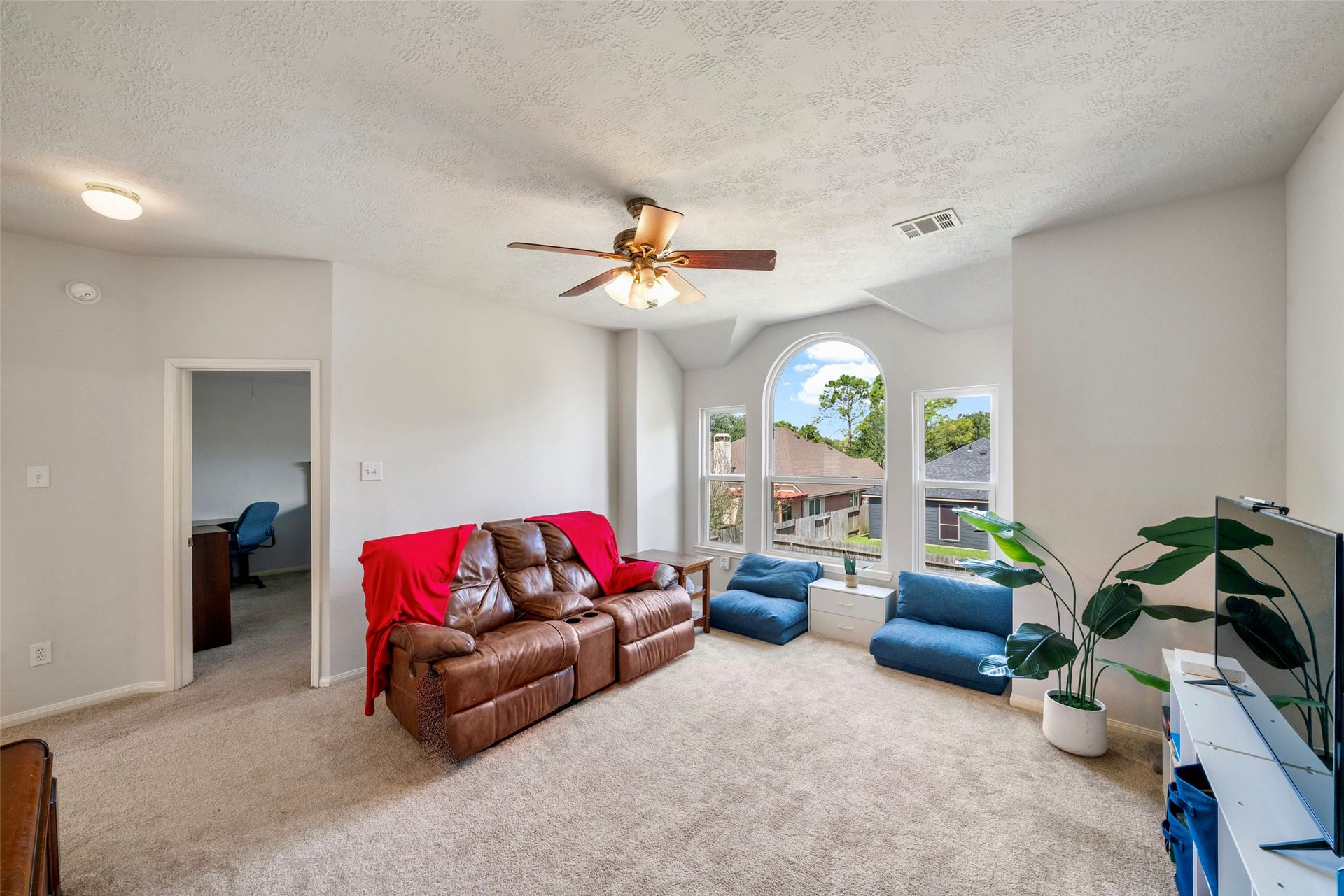 3607 Parkshire Drive, Pearland, TX 77584 Bright and inviting game room with a charming arched window, plush carpeting, and ceiling fan, offering an inviting atmosphere for games, living, movie night, etc.