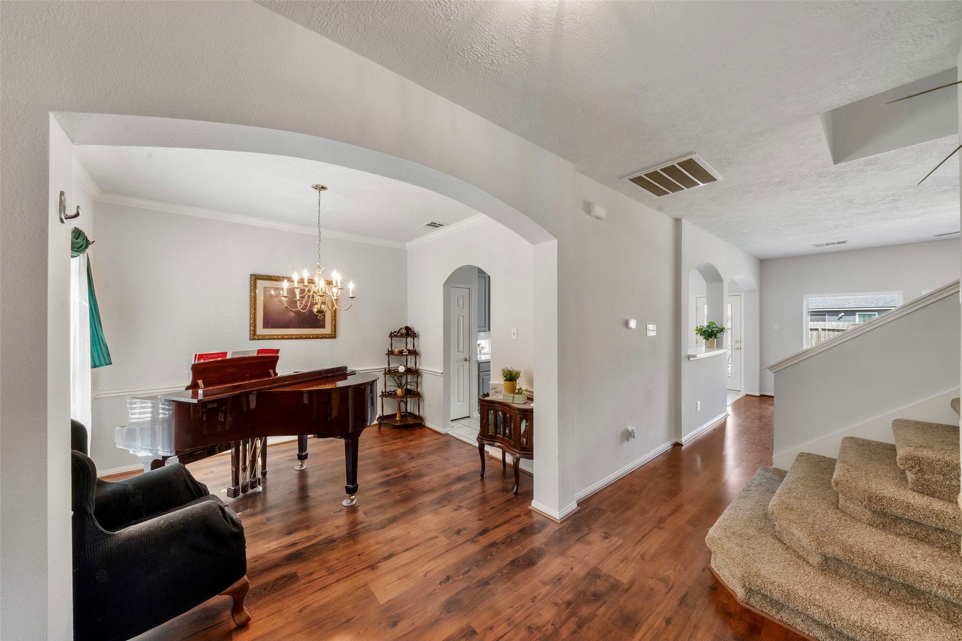 3607 Parkshire Drive, Pearland, TX 77584 Elegant living space featuring rich flooring, plenty space for a baby grand piano or dining table, under a stylish chandelier, and a graceful staircase leading to the upper level.