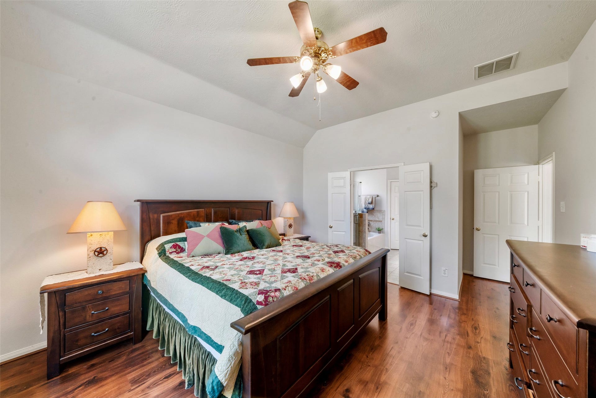 3607 Parkshire Drive, Pearland, TX 77584 Spacious bedroom featuring elegant floors, a cooling ceiling fan, and an en-suite bathroom, creating a relaxing retreat.