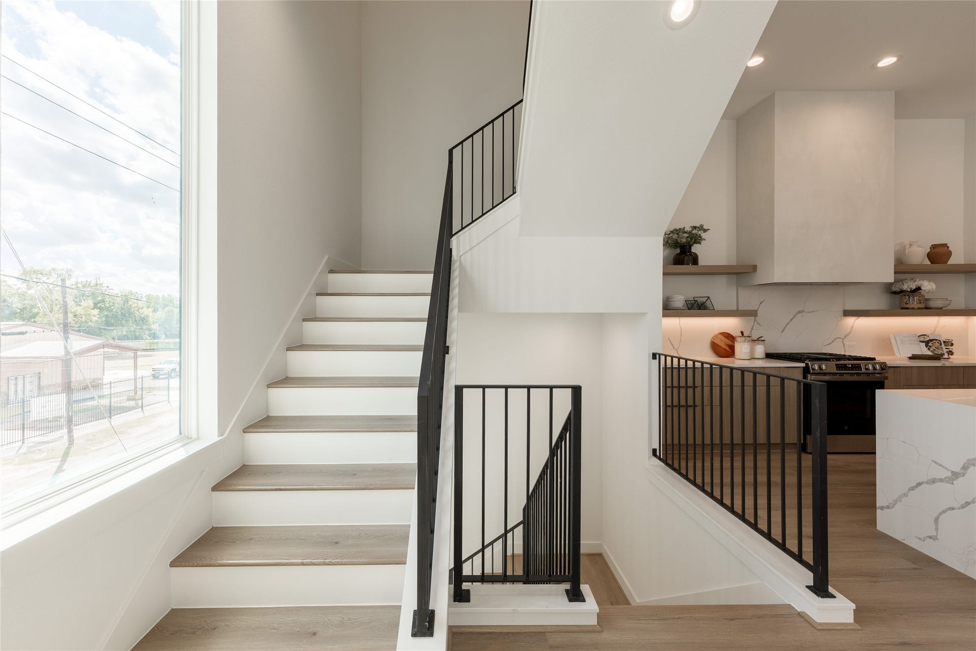 2009 Gregg Street, Houston, TX 77026 Bright and modern staircase with sleek black railings, adjacent to a stylish kitchen featuring open shelving and contemporary finishes.
