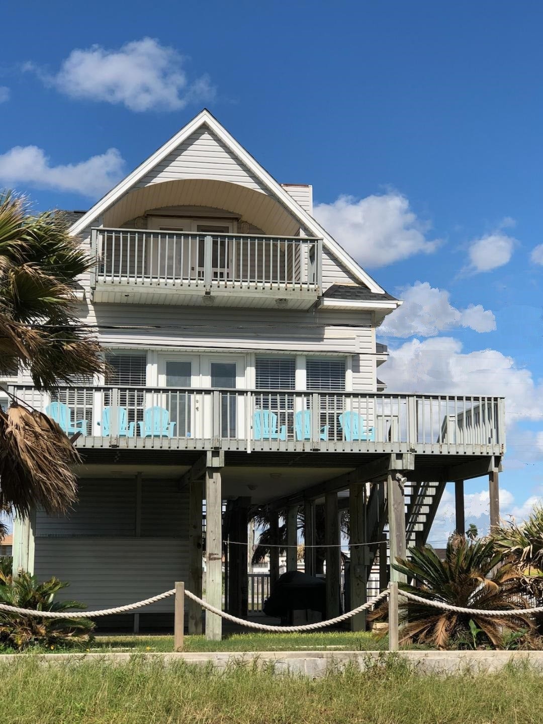 21519 San Luis Pass Road, Galveston, TX 77554 This is a charming elevated beach house with a spacious deck, perfect for enjoying ocean views. It features two levels of outdoor seating, palm trees, and a light, airy design. Ideal for coastal living.