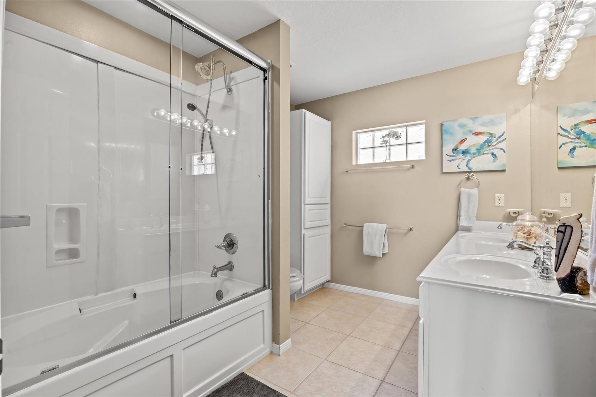 21519 San Luis Pass Road, Galveston, TX 77554 This clean, modern design includes a glass-enclosed shower-tub combo, a double-sink vanity with ample counter space, and neutral tile flooring. Bright lighting and a small window enhance the airy feel.