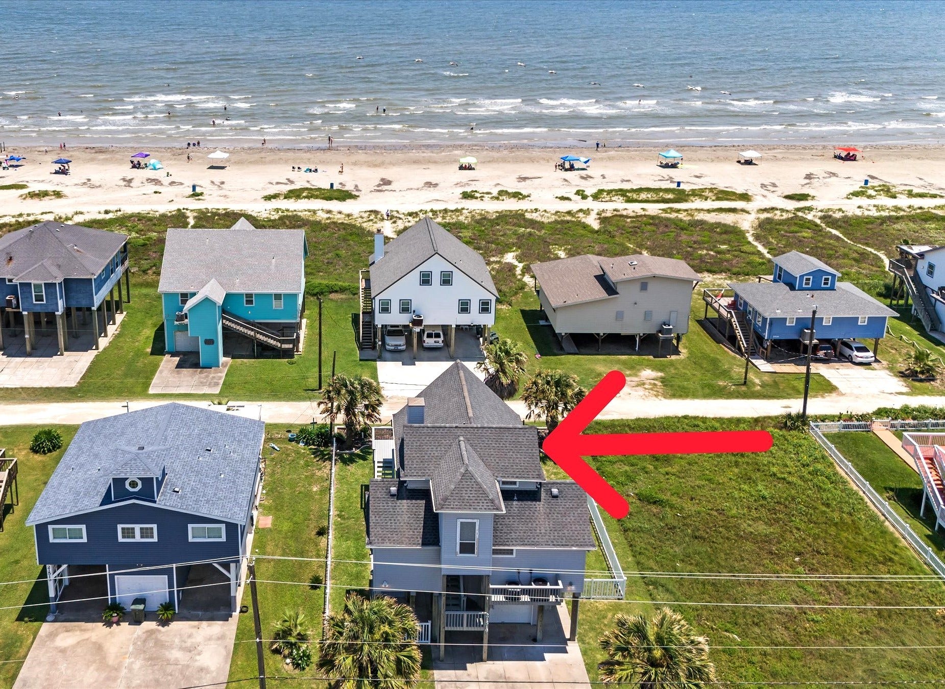 21519 San Luis Pass Road, Galveston, TX 77554 This photo shows this beachside home with a prime location just steps from the ocean. The house features elevated construction for the best views. An arrow highlights this specific home for sale.