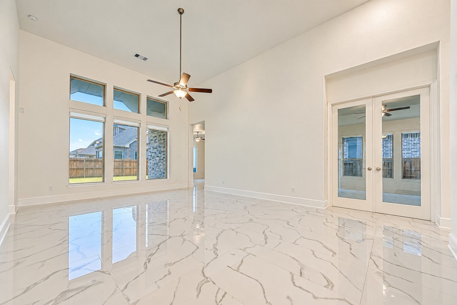 12215 Mackinchan Street, Richmond, TX 77407 A bright, modern family room featuring a dramatic wall of windows that fills the space with abundant natural light, creating an inviting atmosphere for everyday living and elegant entertaining