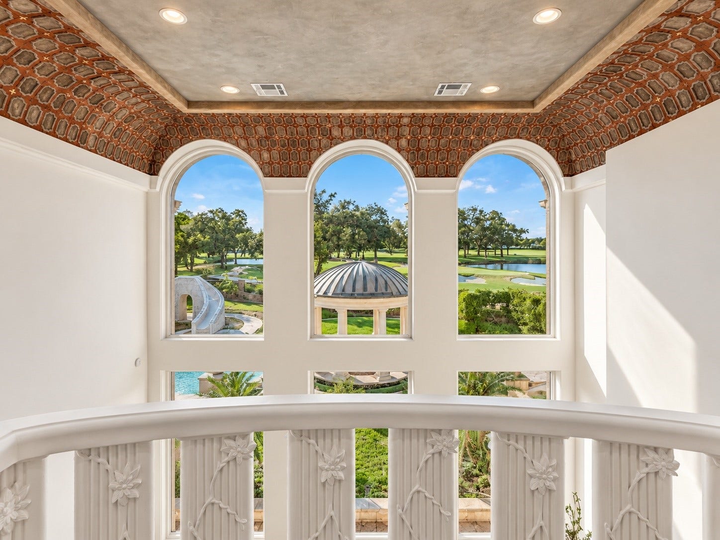 23 Beacon Hill Hill, Sugar Land, TX 77479 Beautiful arched windows frame sweeping views of the landscaped grounds and golf course setting, bringing natural light and scenic surroundings into the upper levels of the estate.