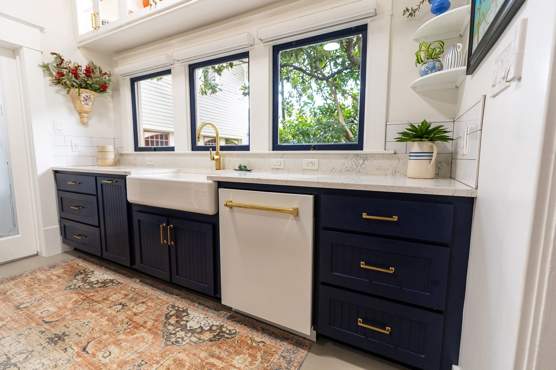 1841 Cortlandt Street, Houston, TX 77008 I love this kitchen, 30" farmhouse sink, dark navy wood cabinets custom made on site, white quartz countertops with a little blue design running throughout the quartz, special gold faucet and cabinet pulls. Enjoy three original windows looking at green plants while you prepare dinner. Upper cabinets are lit up and have glass fronts.