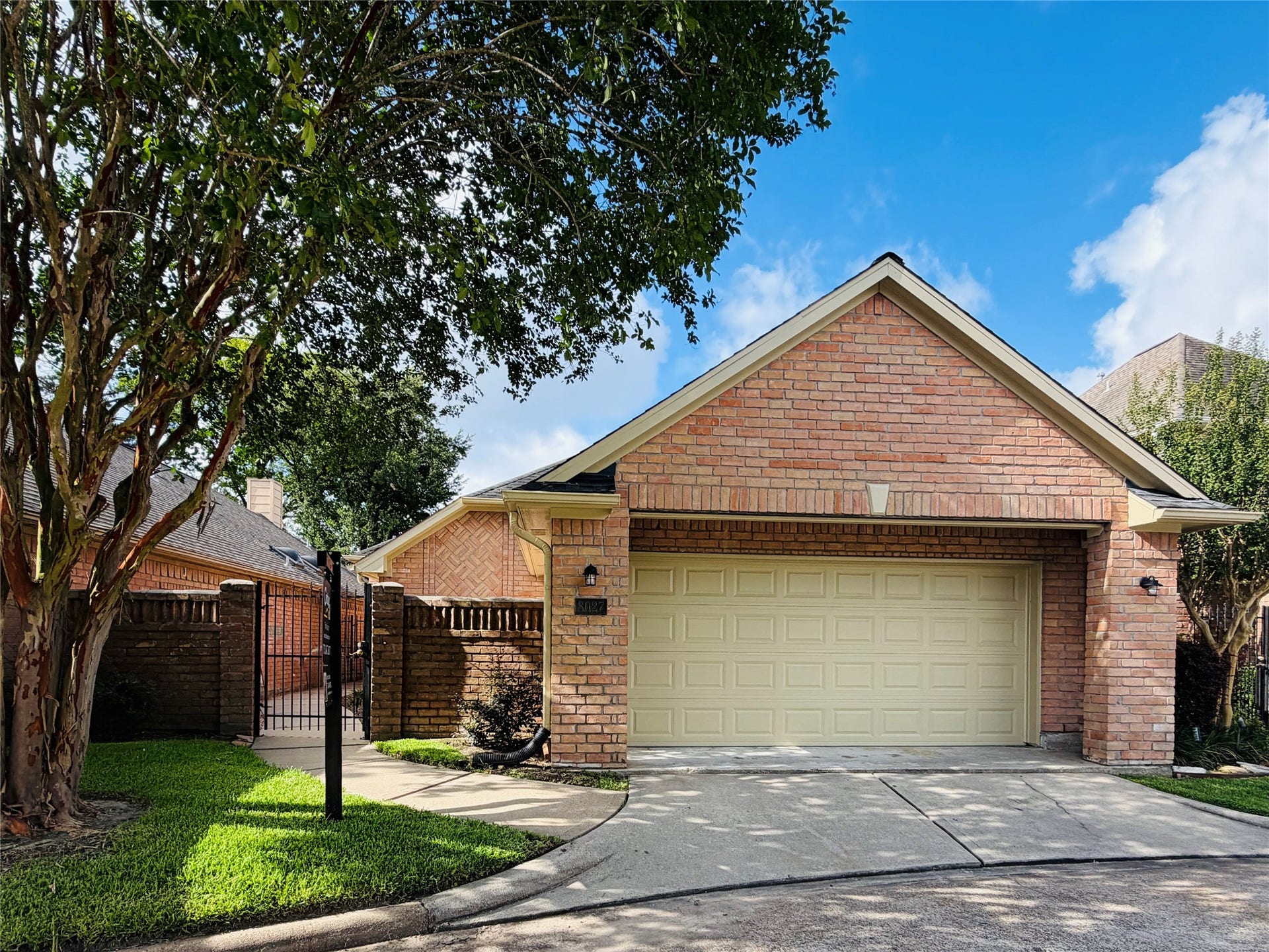 8027 Oakwood Garden Street, Houston, TX 77040 Welcome home! Located in a gated patio home community. This charming brick house has a two-car garage and a gated entrance. The property is surrounded by lush greenery and mature trees, creating a welcoming and private atmosphere.
