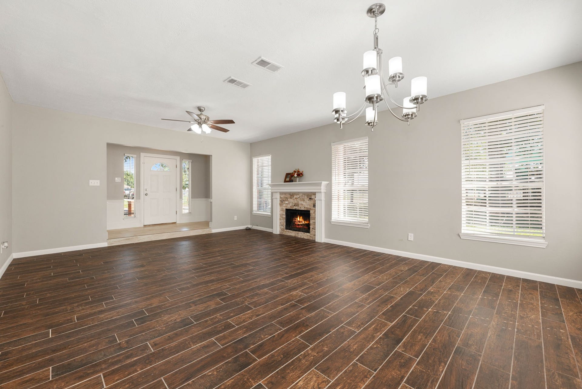 Another look at the spacious living area showcases the stacked-stone fireplace, wood-look tile flooring, and open flow into the dining space.