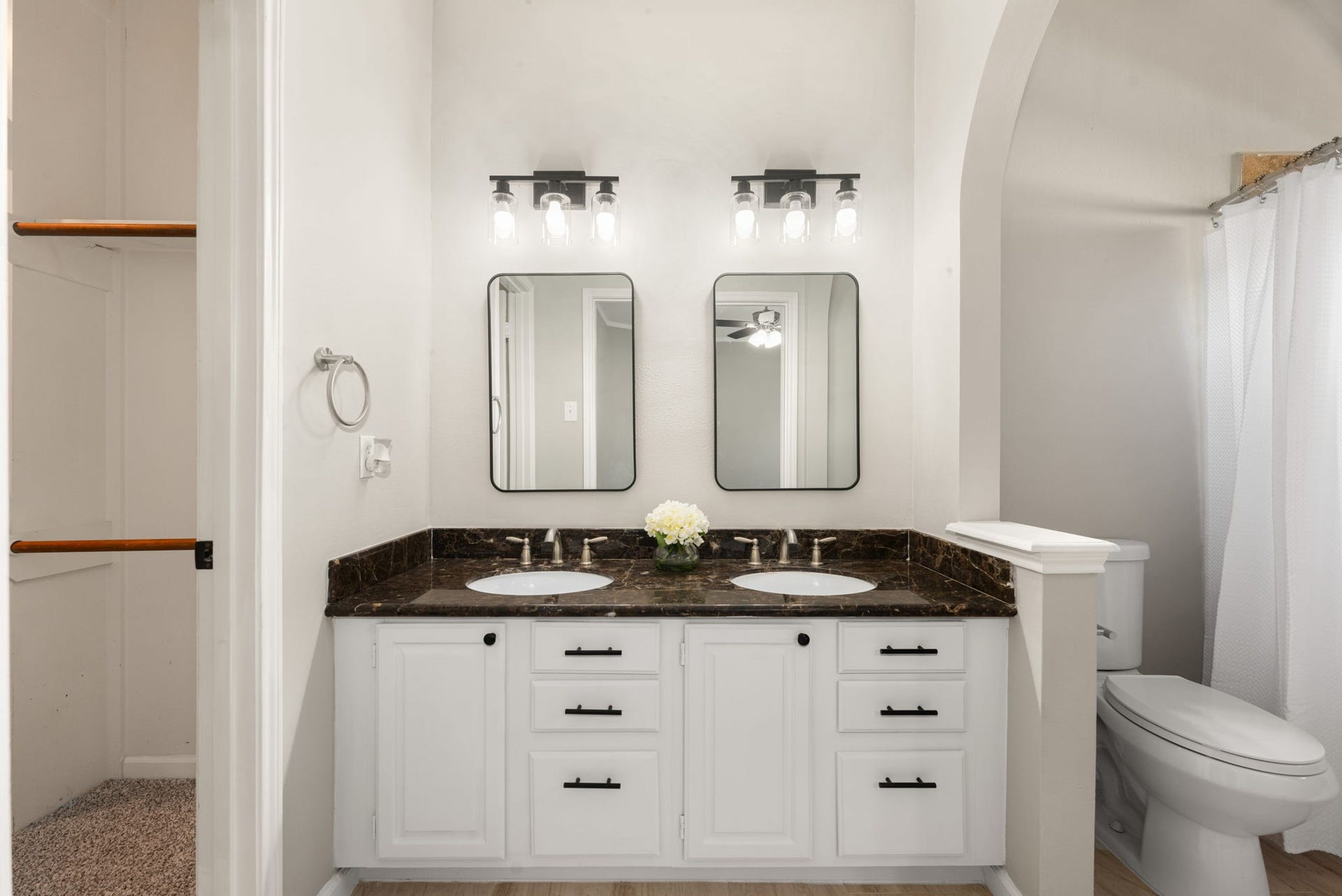 The refreshed primary bathroom features a dual-sink vanity, updated lighting, and new mirrors that give the space a clean, modern look.