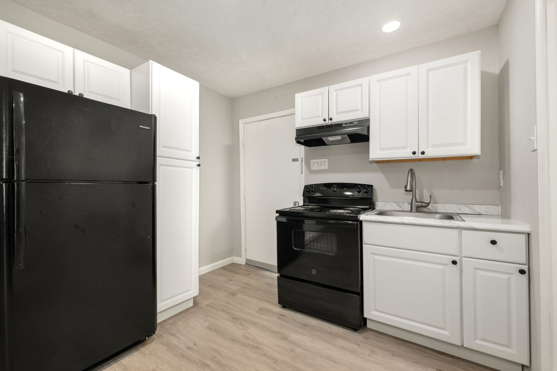 The apartment's separate kitchen features a full-size refrigerator, range, and cabinet storage, adding convenience and flexibility to this unique space.
