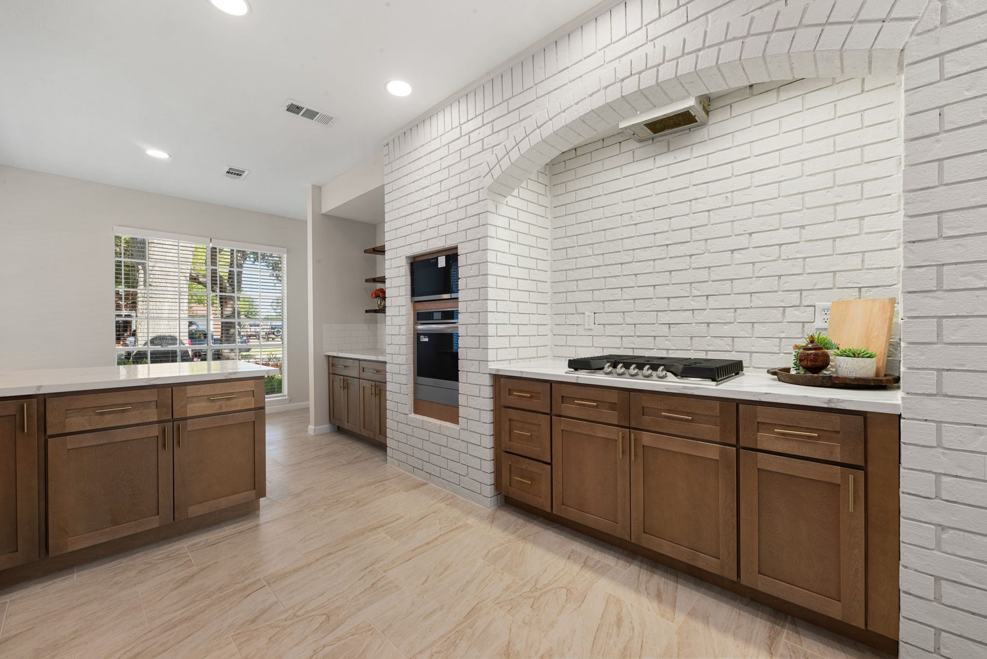A closer look at the kitchen highlights the new cabinetry and appliances, with the original brick archway adding a touch of character to the fresh, updated design.