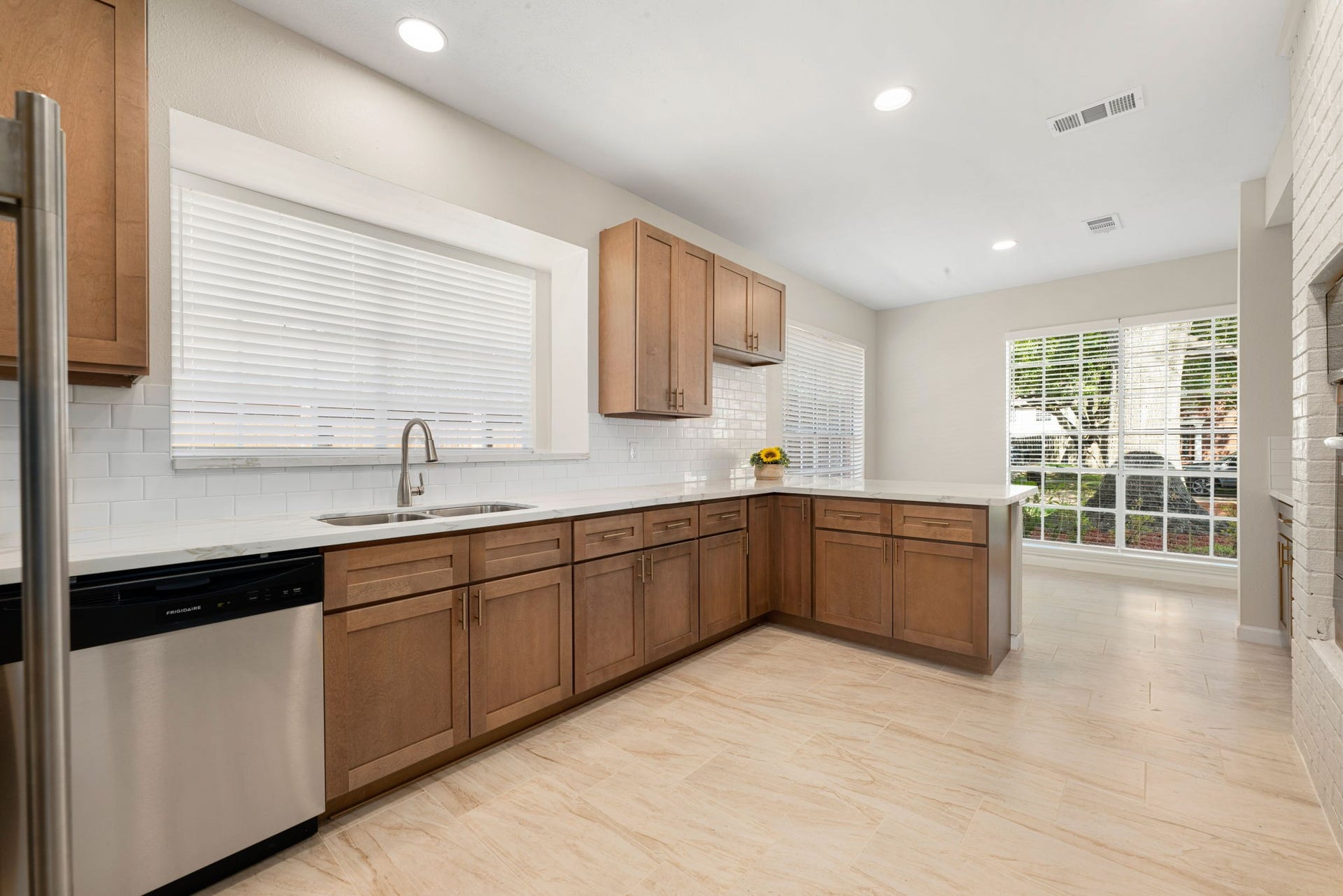 The beautifully remodeled kitchen boasts gleaming quartz countertops, a chic subway tile backsplash, and a charming white-painted brick archway framing the built-in wall ovens.