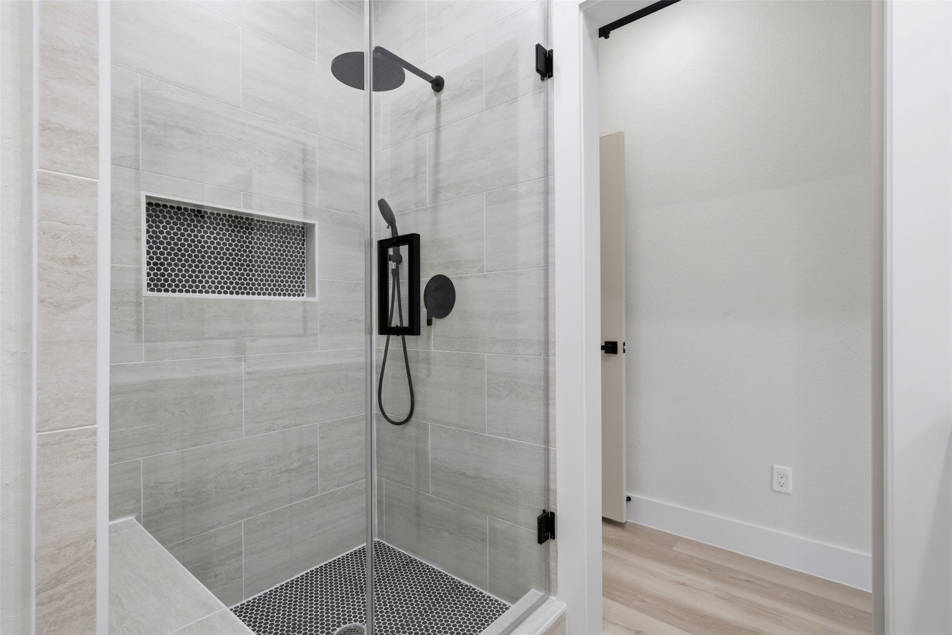 3201 & 3205 Berry Street, #A/B, Houston, TX 77004 Sleek and modern shower with elegant tilework, glass doors, and a convenient built-in niche for storage.