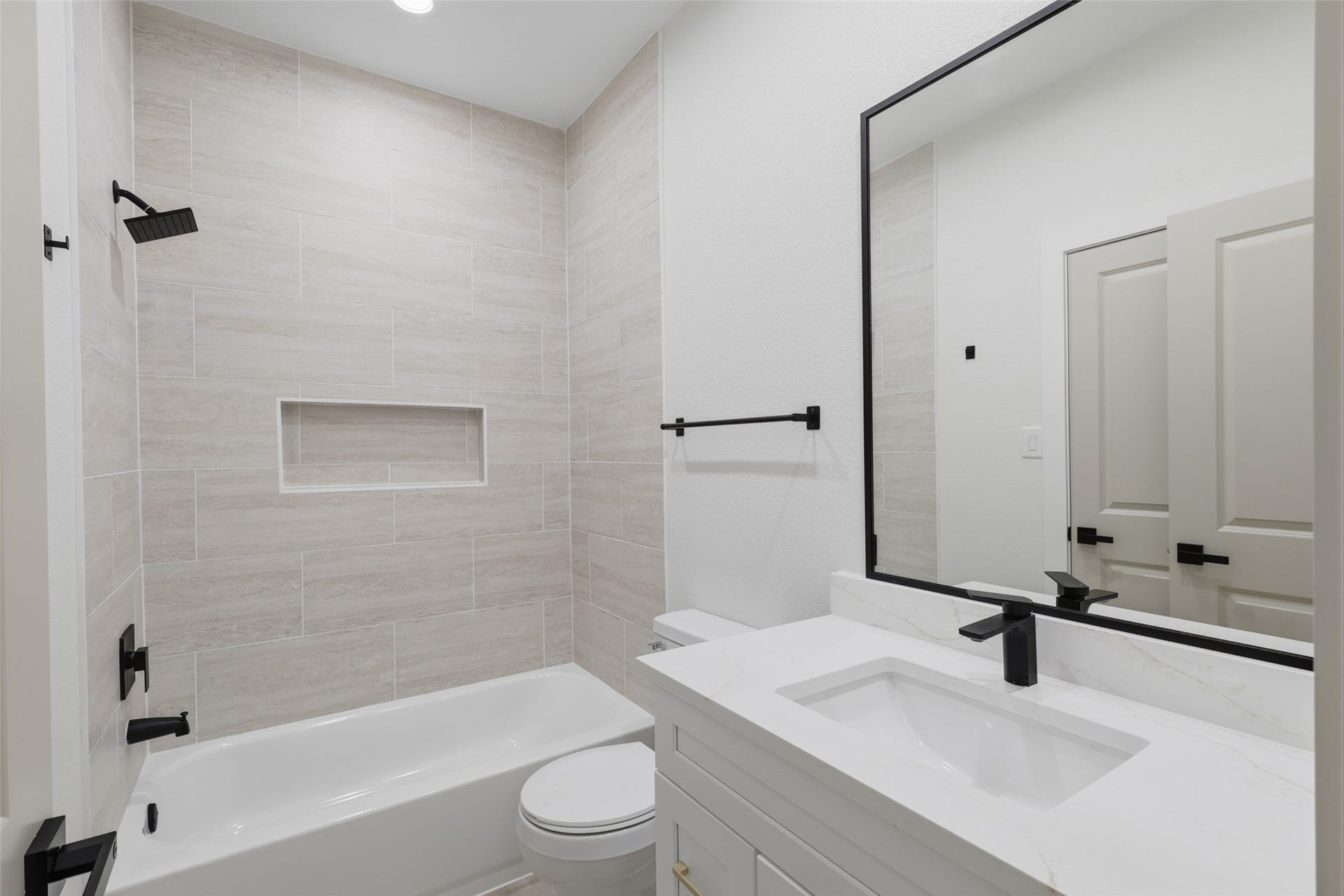 3201 & 3205 Berry Street, #A/B, Houston, TX 77004 Modern bathroom featuring sleek black fixtures, a spacious vanity with a large mirror, and a stylish tiled shower-tub combo.