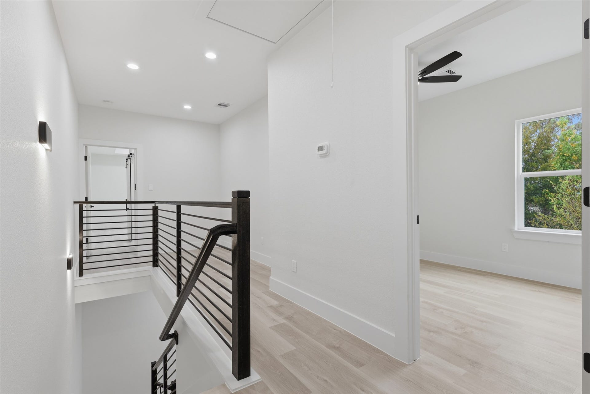 3201 & 3205 Berry Street, #A/B, Houston, TX 77004 Bright and modern upstairs landing with sleek railings, recessed lighting, and access to a sunlit room, creating a welcoming and open atmosphere.