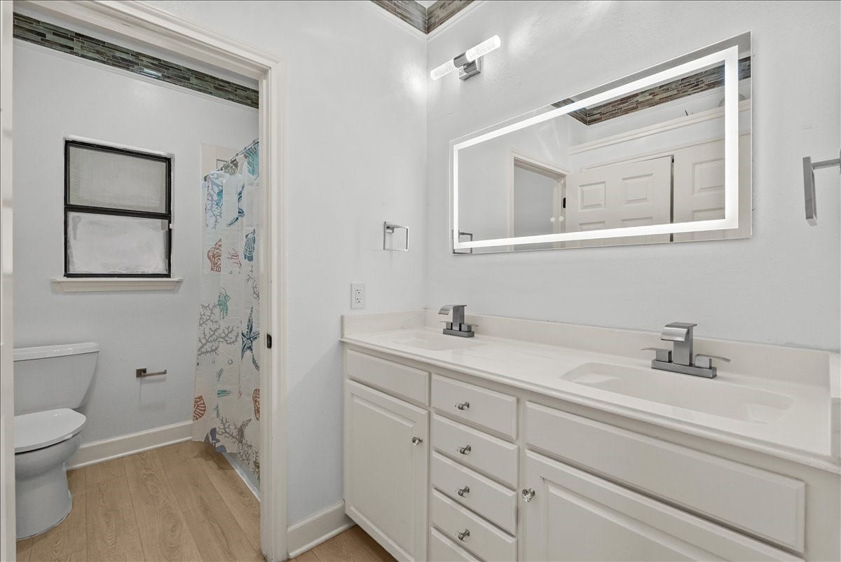 9700 Jay Road, Hitchcock, TX 77563 Thoughtfully designed guest bath featuring a dedicated vanity area with a modern illuminated mirror, while a separate enclosed space houses the tub/shower combination and toilet for added privacy and convenience.