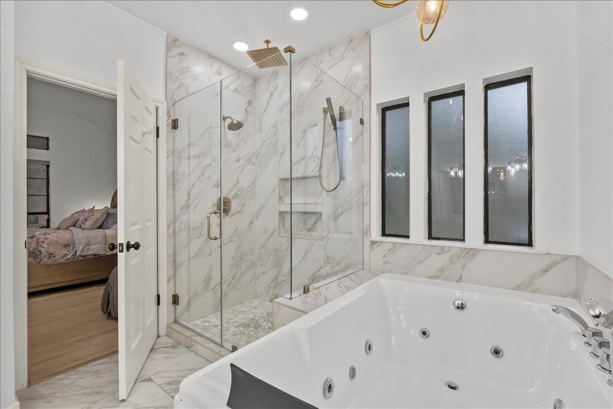 9700 Jay Road, Hitchcock, TX 77563 Step into your own private spa retreat featuring a stunning two-person jetted soaking tub with hydrotherapy jets, LED chroma lighting, waterfall faucet, and dual headrests, along with a custom Delta shower system offering dual shower heads, rainfall shower, and multi-function controls.