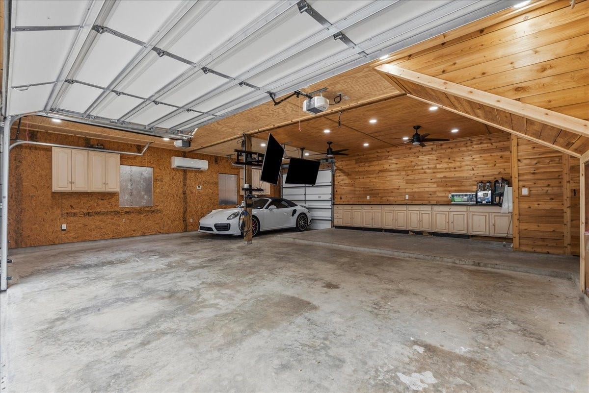 9700 Jay Road, Hitchcock, TX 77563 More than just a garage, this space was designed for enjoyment and functionality with custom-style beadboard and shiplap details, abundant cabinetry, granite countertops, a built-in entertainment area with two TVs, and an EV charging station. Whether used as a workshop, game space, or gathering area, this garage offers endless possibilities.