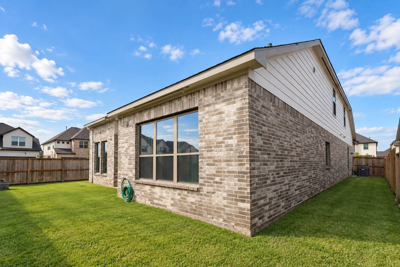 3165 Stingray Cove Drive, Katy, TX 77493 Large windows line the rear elevation, allowing natural light to fill the home while overlooking the grassy backyard. The brick exterior offers timeless appeal, and the fenced backyard provides ample room to create a personalized outdoor retreat.