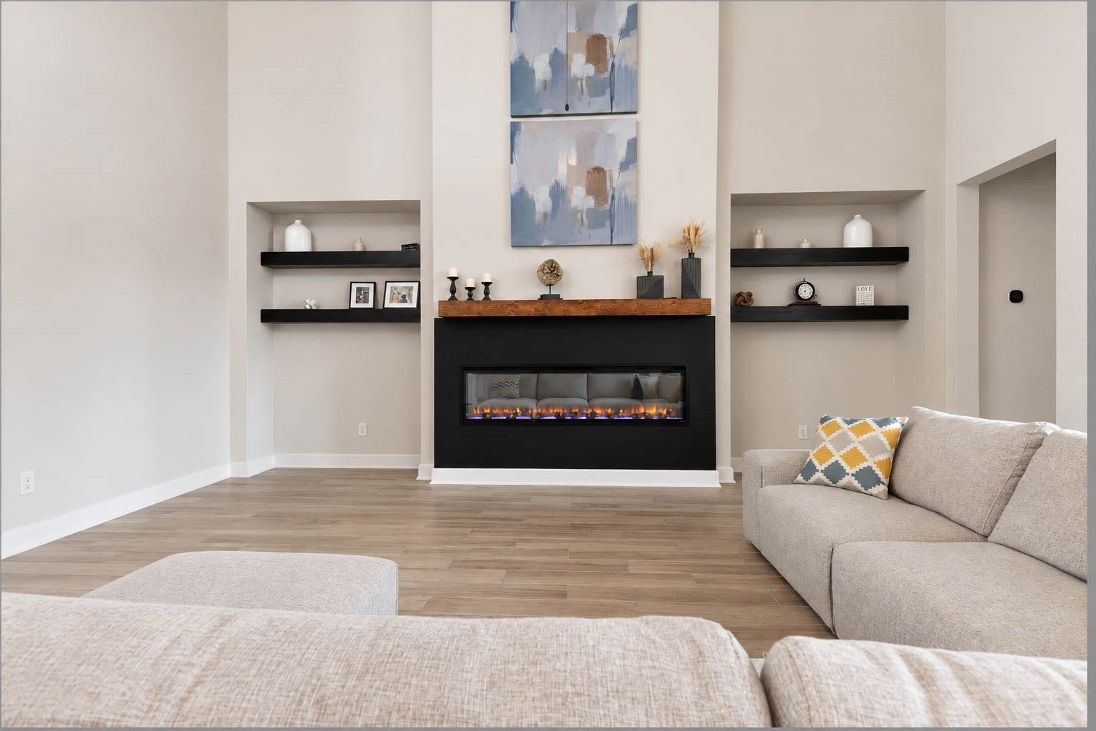 3165 Stingray Cove Drive, Katy, TX 77493 A sleek linear electric fireplace creates a striking focal point, finished with a bold surround, warm wood mantel, and recessed niches accented by floating shelves for a custom, designer touch.