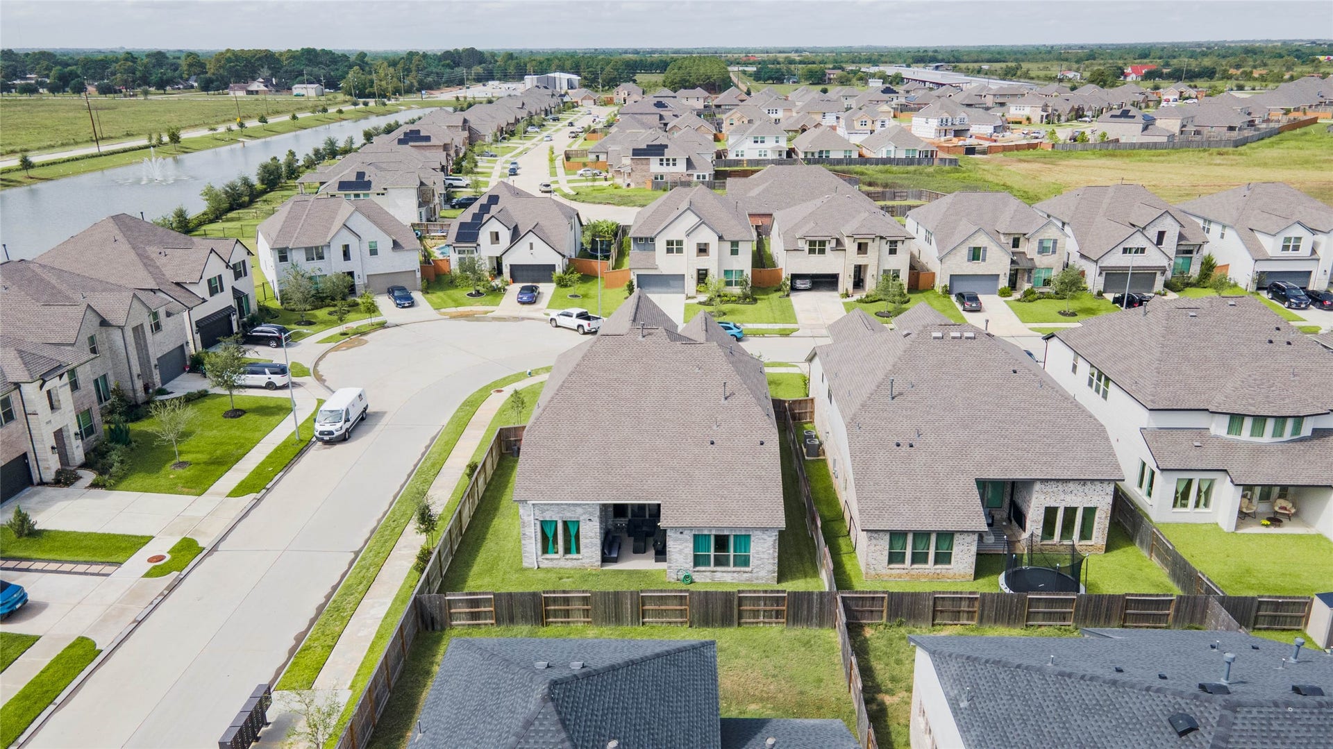 3165 Stingray Cove Drive, Katy, TX 77493 Looking toward the rear of the property, this aerial highlights the fenced backyard, covered outdoor living area, and surrounding neighborhood. Beyond the home, Sunterras attractive streetscape and nearby lake create a picturesque backdrop for this growing Katy community.