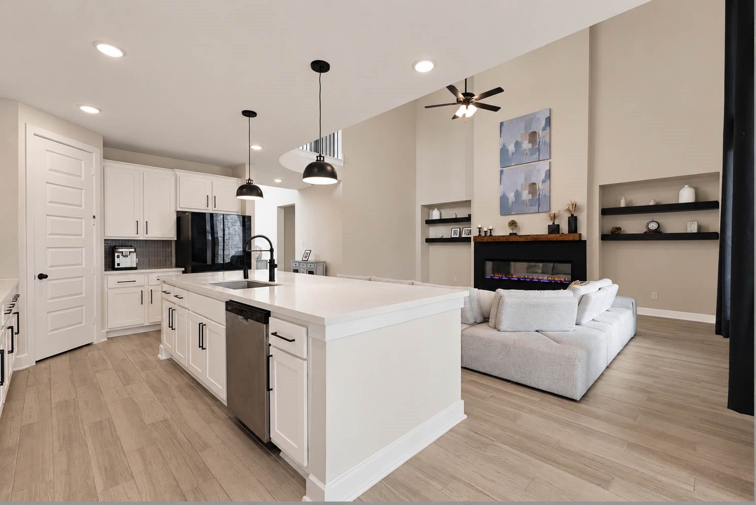 3165 Stingray Cove Drive, Katy, TX 77493 This perspective perfectly captures the seamless relationship between the kitchen and soaring family room. The oversized island overlooks the living space, allowing conversation to flow easily between the two areas, while the family rooms sleek fireplace and built-in display niches create an impressive backdrop.