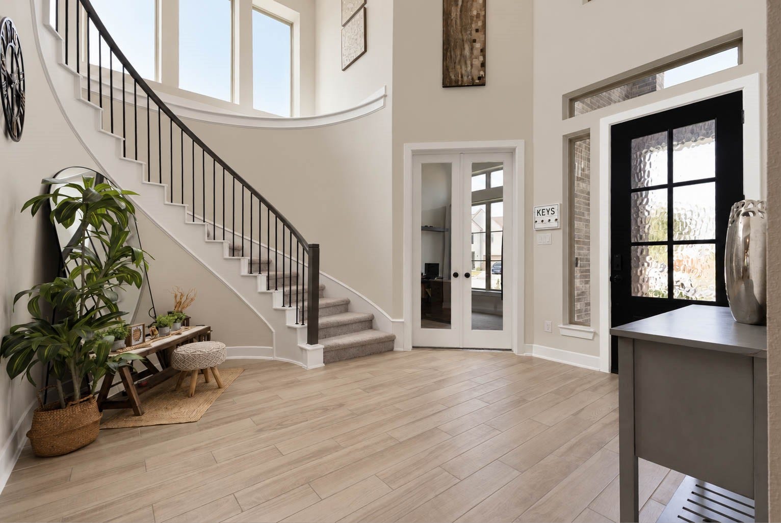 3165 Stingray Cove Drive, Katy, TX 77493 Another view of the dramatic foyer showcases the graceful curved staircase framed by tall windows that fill the entry with natural light. The striking front door is accented by textured glass, a sidelight, & transom windows, while glass French doors open to the private home office.