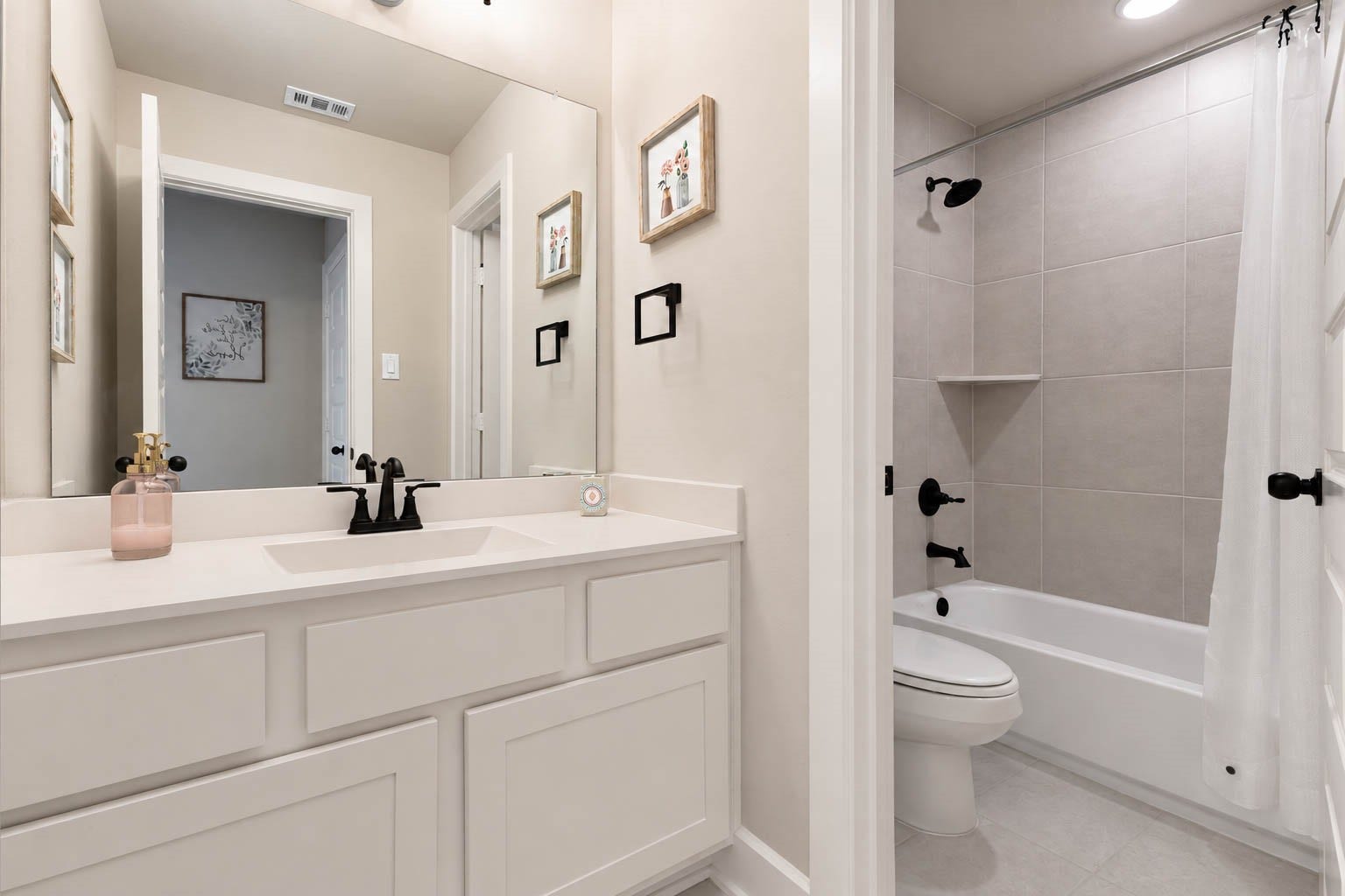 3165 Stingray Cove Drive, Katy, TX 77493 The upstairs bath offers a clean, polished design with a spacious vanity, expansive mirror, and dark fixtures for a striking contrast. A separate tub/shower area features large-format tile extending to the ceiling, creating a stylish and functional space for the upstairs bedrooms.