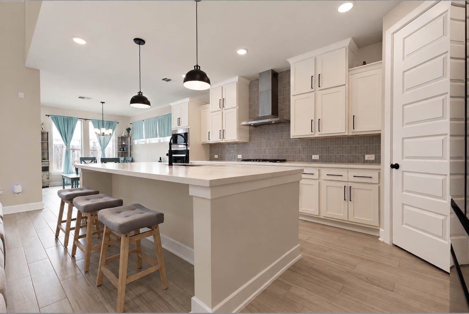 3165 Stingray Cove Drive, Katy, TX 77493 Designed with both beauty and function in mind, this sophisticated kitchen offers a streamlined workspace framed by rows of white cabinetry and expansive quartz surfaces. The substantial island provides additional storage and prep space while creating a natural gathering spot between the kitchen and family room.