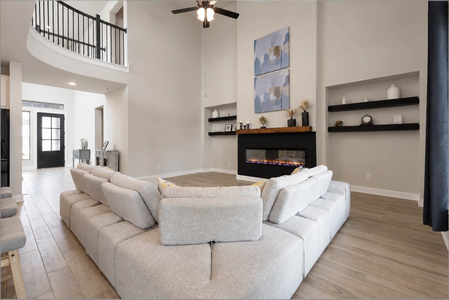 3165 Stingray Cove Drive, Katy, TX 77493 The impressive family room commands attention with its soaring two-story ceiling, grand proportions, and striking architectural design. An elegant second-floor catwalk gracefully overlooks both the family room and entry below, enhancing the homes dramatic sense of scale.