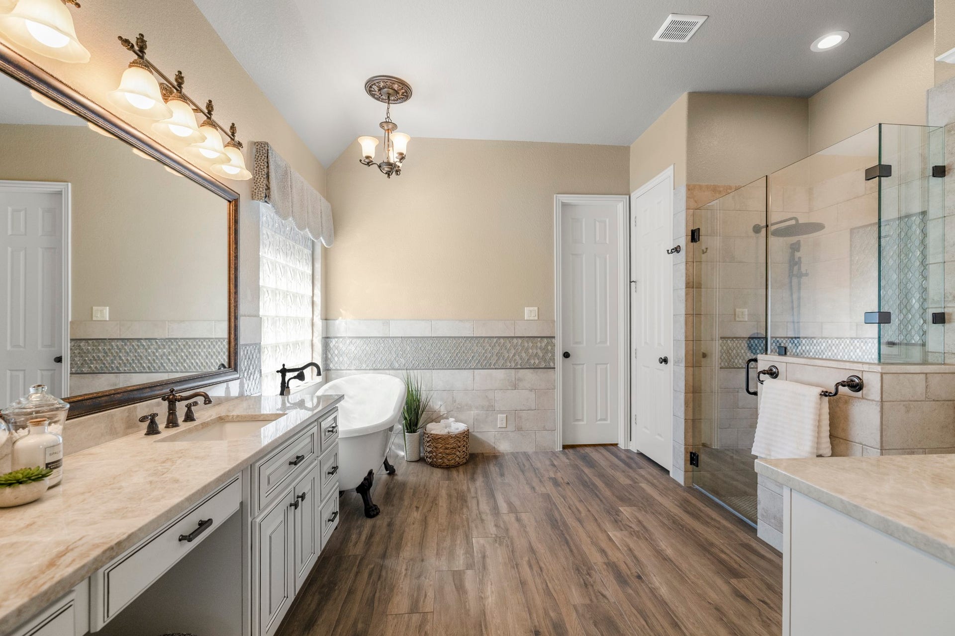 2407 Hendricks Lakes Drive, Spring, TX 77388 Continuing into the remodeled primary bath, the suites upgraded finish comes into focus with Taj Mahal quartzite, Emser tile, dual vanities, a freestanding clawfoot tub, and a glass-enclosed shower. The door straight ahead leads into the walk-in closet, keeping the bath and closet connected in a way that feels polished, private, and easy to live in.