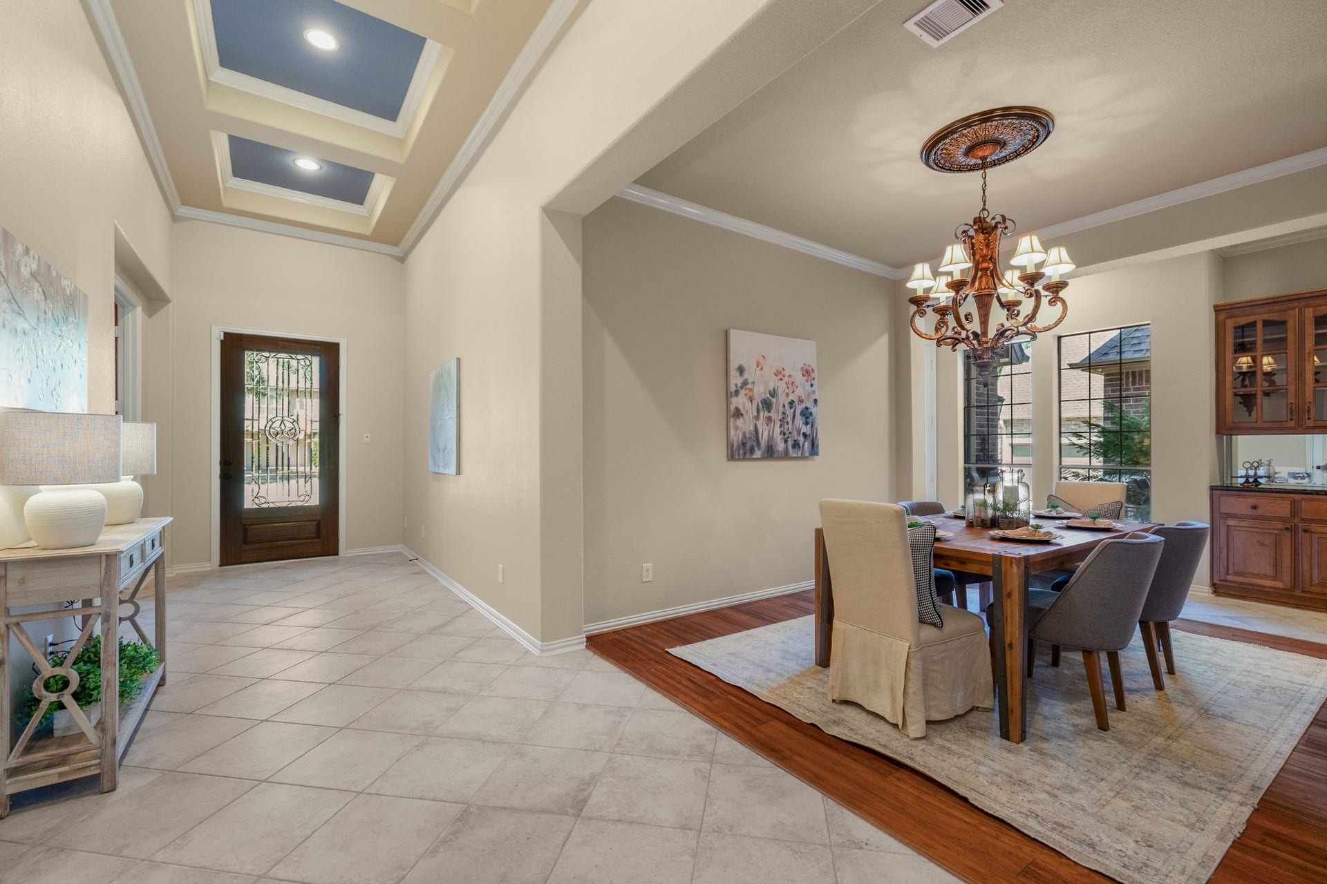 2407 Hendricks Lakes Drive, Spring, TX 77388 Looking back toward the front entry, the foyer highlights tray ceiling accents with crown molding, accent-color insets, and diagonal tile flooring that adds a more custom feel from the first steps inside. The study sits along the left side from this view, while the formal dining room opens to the right with warm wood flooring, creating a polished transition between the front rooms before the home continues toward the kitchen and main living spaces.