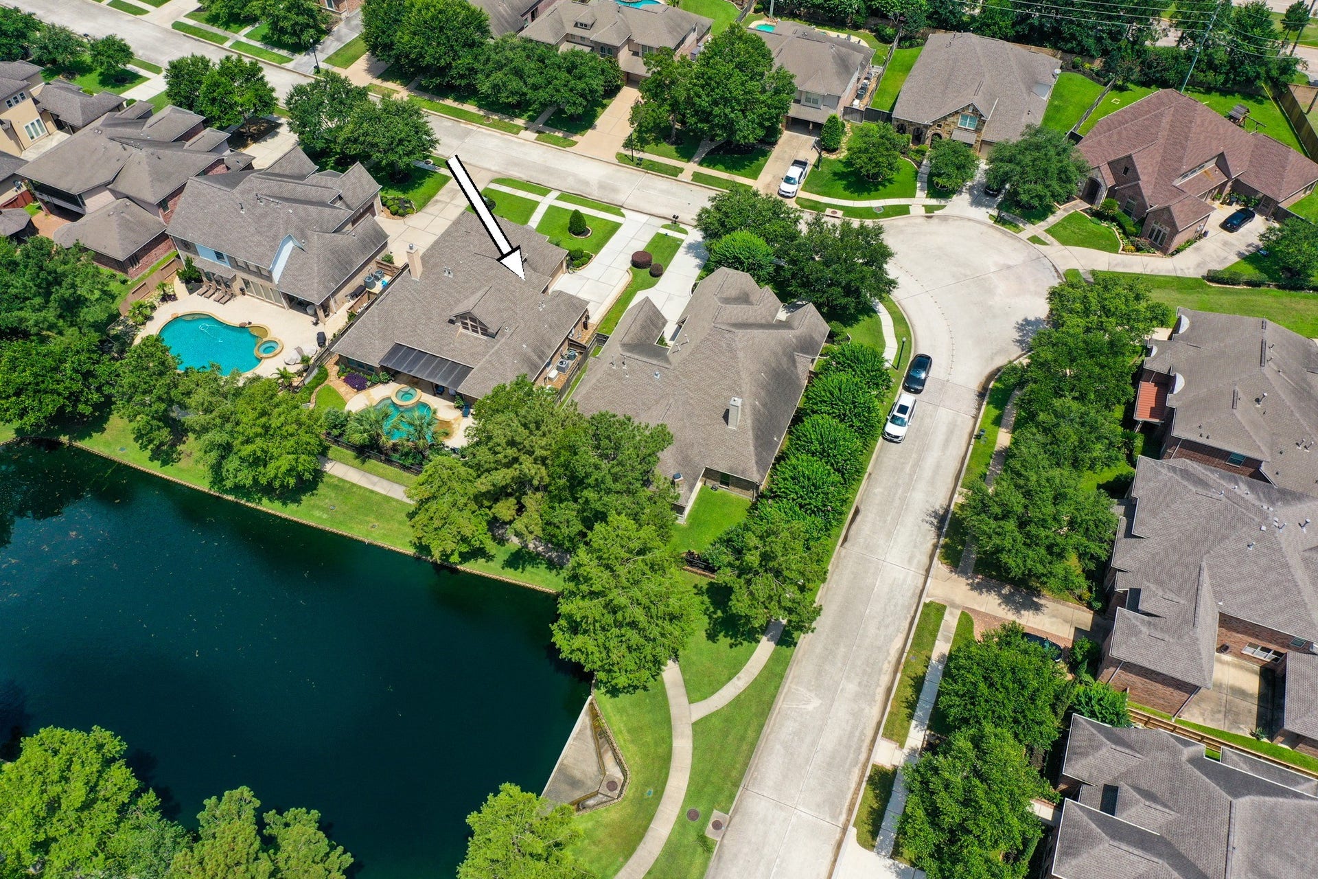 2407 Hendricks Lakes Drive, Spring, TX 77388 From above, the homes water-front setting comes into focus with the walking path, water, neighboring outdoor spaces, and pool/spa all visible. Behind the home, the covered outdoor living area and backyard overlook the water-view backdrop, creating an easy connection to the lake-centered lifestyle of Lakes of Cypress Forest.