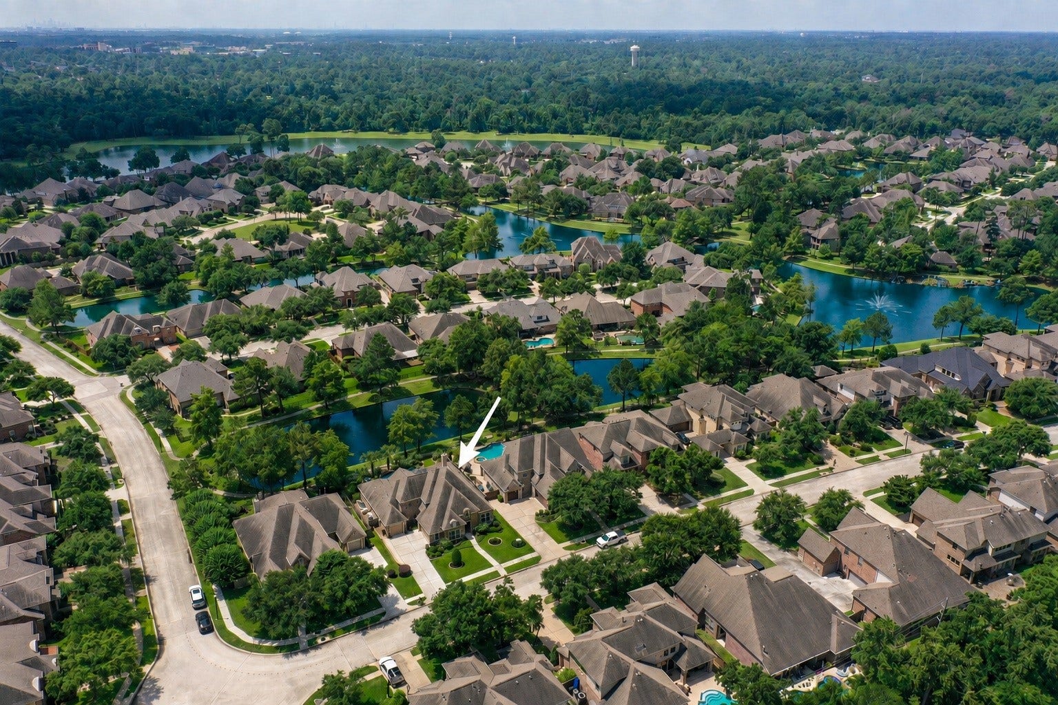 2407 Hendricks Lakes Drive, Spring, TX 77388 Marked from above, 2407 Hendricks Lakes Drive sits within the gated Lakes of Cypress Forest setting, surrounded by water, winding paths, fountains, and established greenery. This view helps place the homes poolside backyard within the larger water-front lifestyle, where the backyard connects naturally to the trails and scenic community spaces just beyond.
