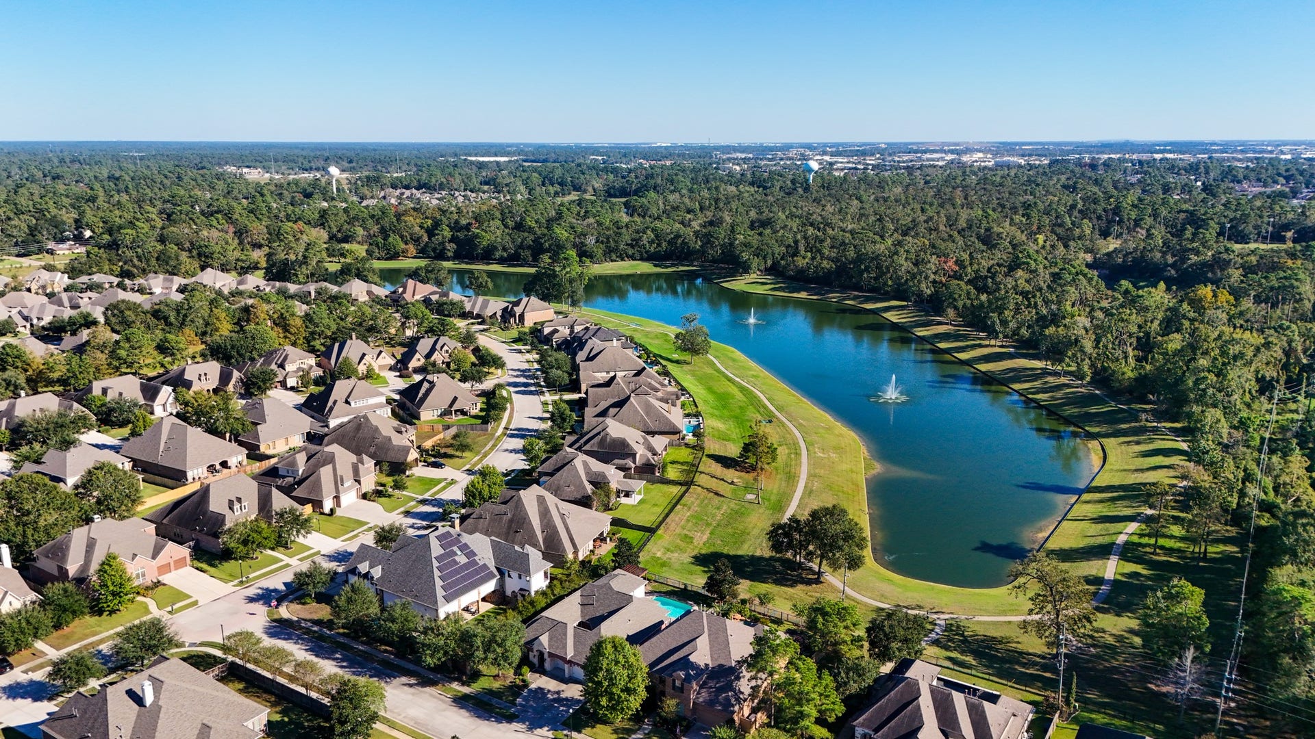 2407 Hendricks Lakes Drive, Spring, TX 77388 Wide aerial views show the scale of Lakes of Cypress Forest, with water, fountains, winding streets, and a wooded backdrop shaping the neighborhoods scenic feel. For buyers drawn to outdoor living, this perspective helps connect the homes poolside, water-front setting to the larger community lifestyle of lakes, paths, and green space.