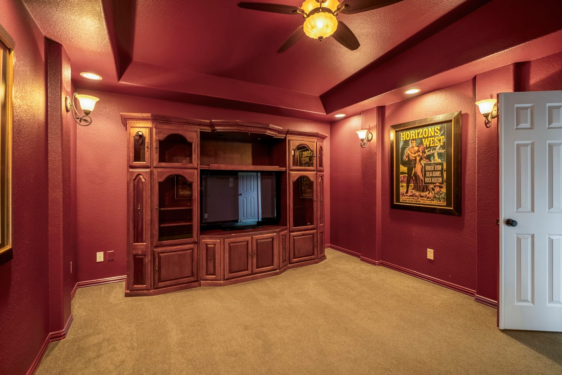 2407 Hendricks Lakes Drive, Spring, TX 77388 Inside the media room, the upstairs retreat shifts into a true movie-night setting with deeper wall color, a ceiling fan, and built-in glass-front cabinetry that gives the room a finished, lounge-like feel. Positioned just off the game room, this space keeps entertainment upstairs with the nearby half bath close by, creating a separate level for watching, playing, and unwinding.