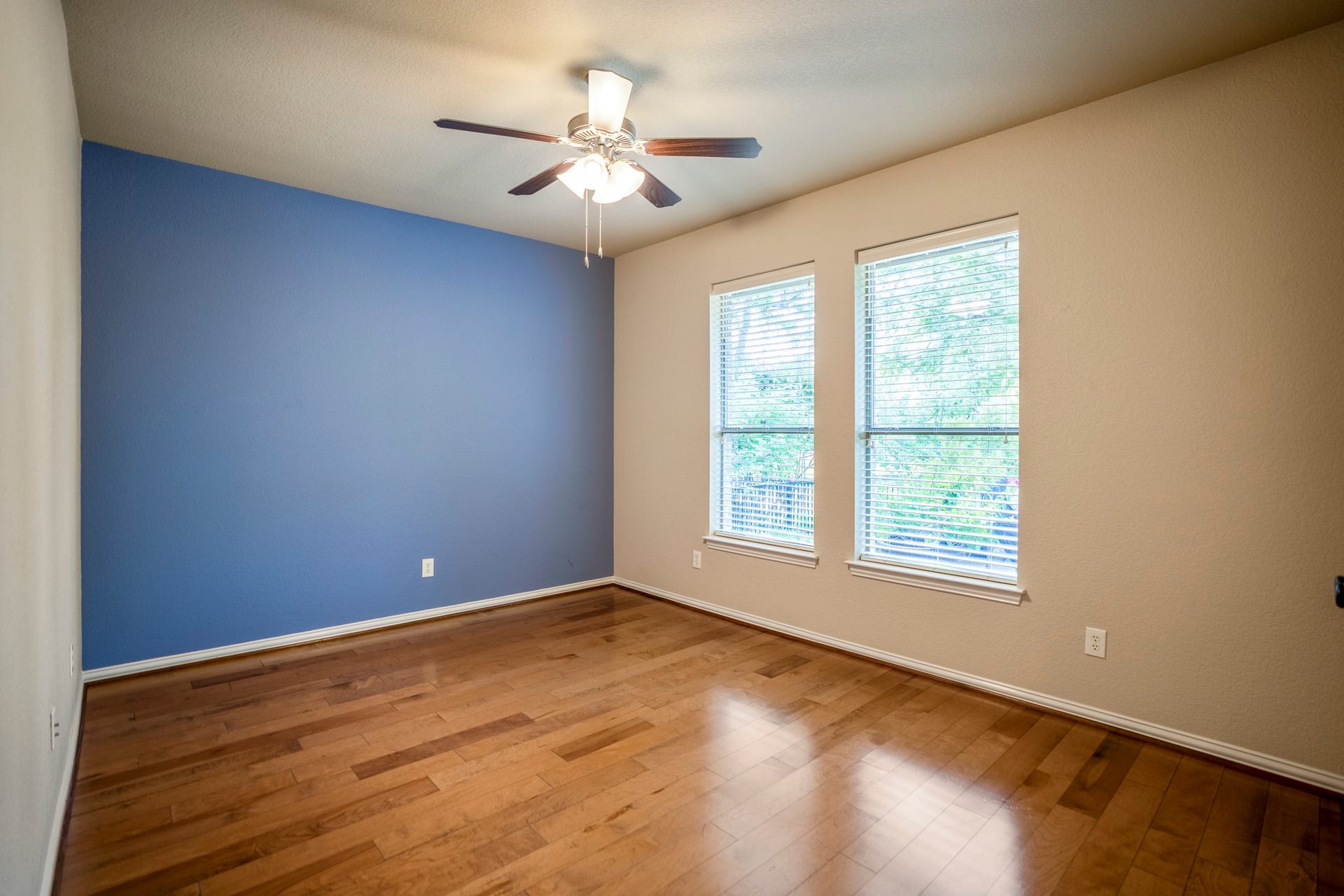2407 Hendricks Lakes Drive, Spring, TX 77388 Moving toward the back of the home near the breakfast nook, this third bedroom brings in natural light through two windows and continues the homes more custom feel with warm wood flooring and a blue accent wall. Its location near the rear bedroom hall keeps these additional bedrooms close to the kitchen and breakfast area while still set apart from the main living room flow.