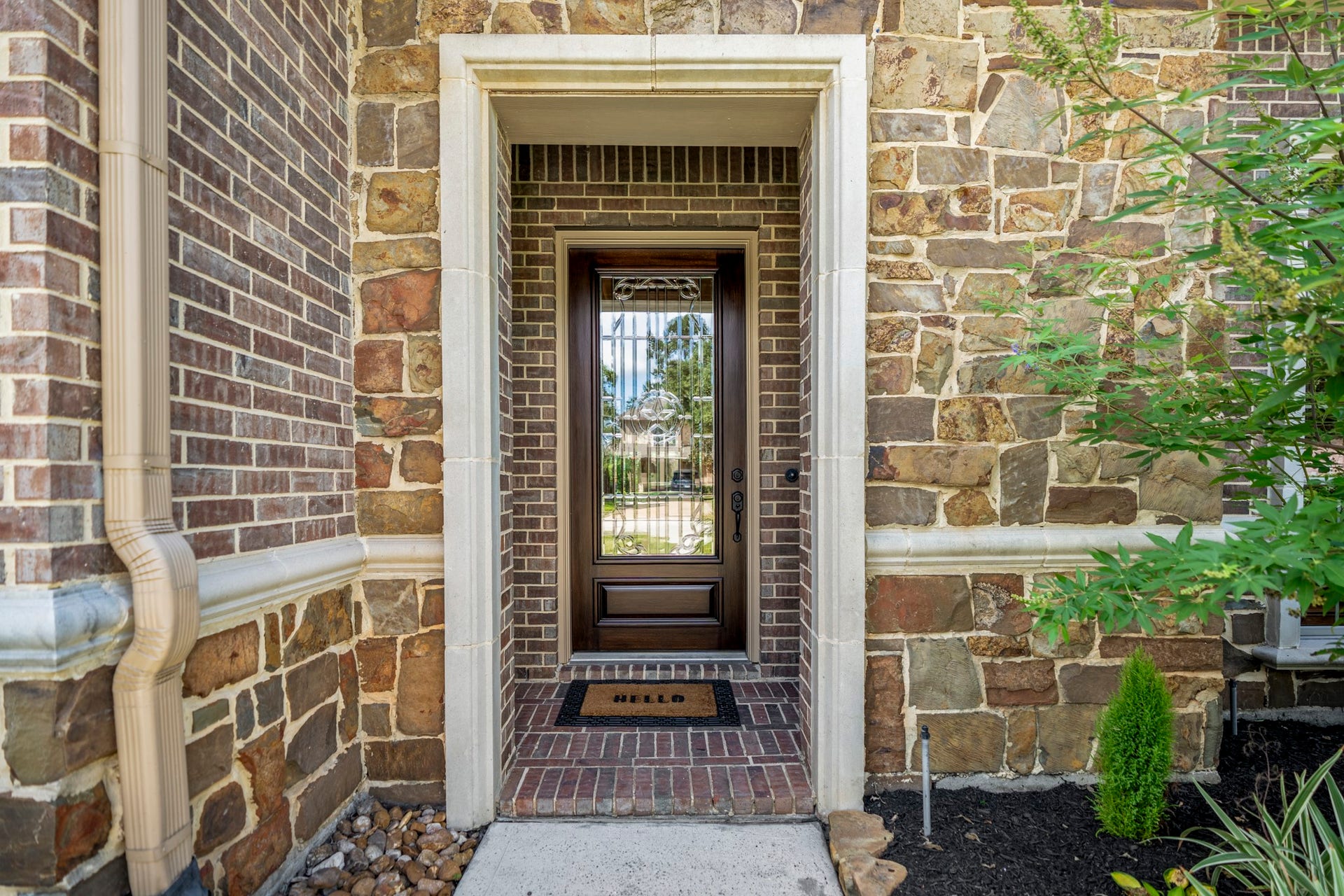 2407 Hendricks Lakes Drive, Spring, TX 77388 At the front entry, brick-and-stone detailing, a recessed porch, and a decorative glass door with Texas star detailing create a polished welcome into the home. This close-up gives buyers a first feel for the homes elevated exterior finishes before the walkthrough moves inside.
