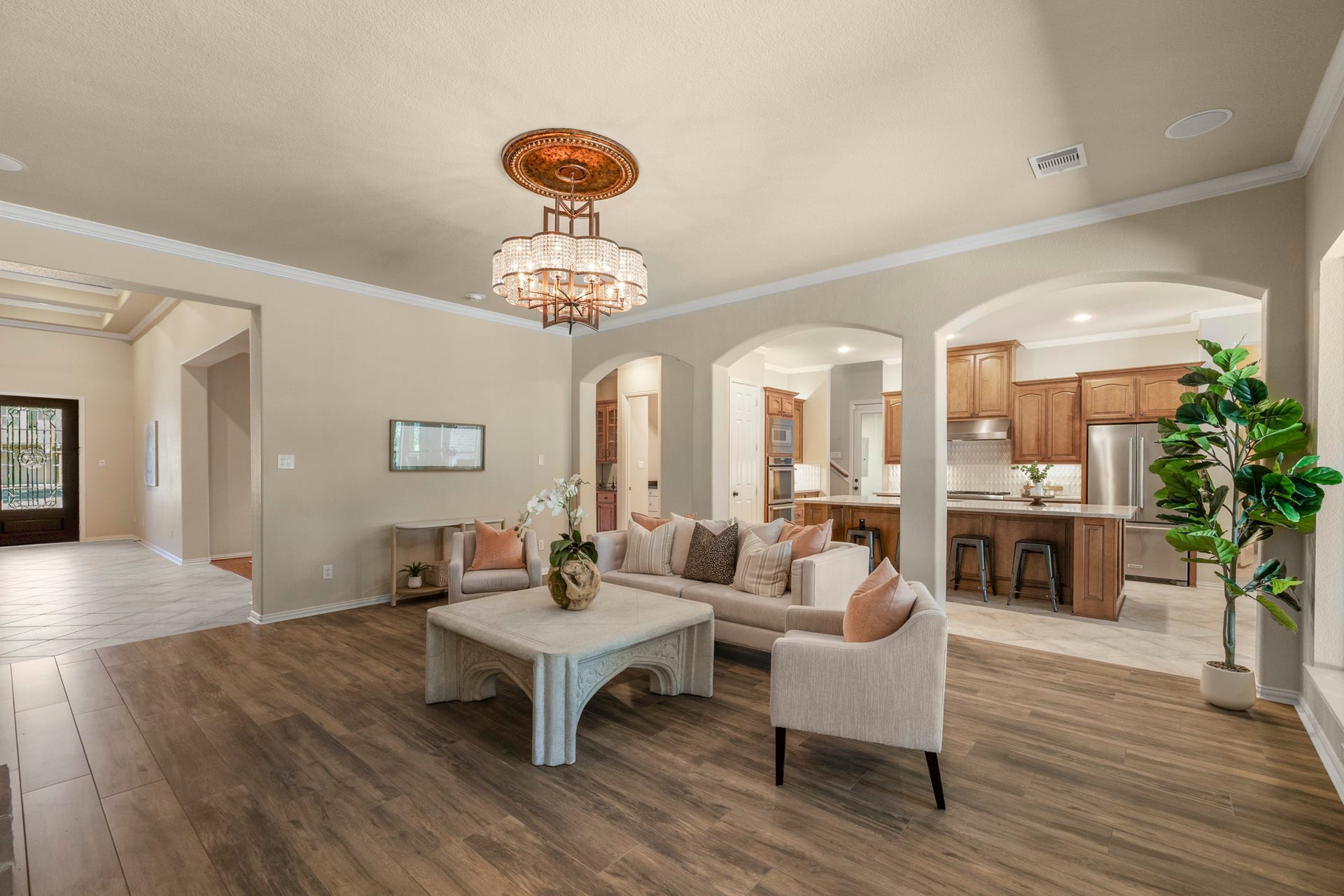 2407 Hendricks Lakes Drive, Spring, TX 77388 Pulled farther back, the living room shows how the main level gathers around one central space, with the kitchen open on the right and the fireplace framed by custom lighted built-ins ahead. The view keeps the homes entertaining flow easy to follow, connecting the kitchen, breakfast area, and living room before the walkthrough continues toward the poolside backyard and water-view setting beyond.