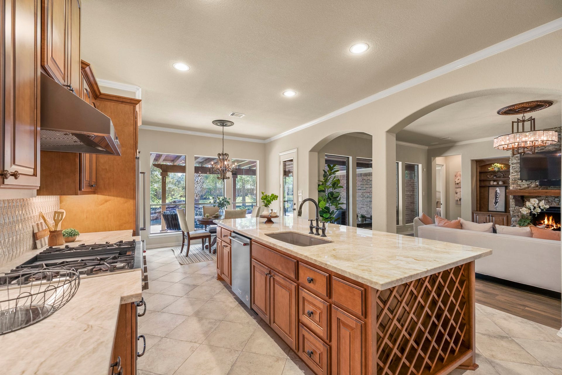 2407 Hendricks Lakes Drive, Spring, TX 77388 The island draws the space together with Taj Mahal quartzite, rich Benedettini cabinetry, and undercabinet lighting giving the room its custom, elevated feel. The breakfast nook sits ahead near the windows, pulling natural light toward the back of the home, while the arched openings on the right keep the kitchen connected to the living room and the poolside, water-front setting beyond.