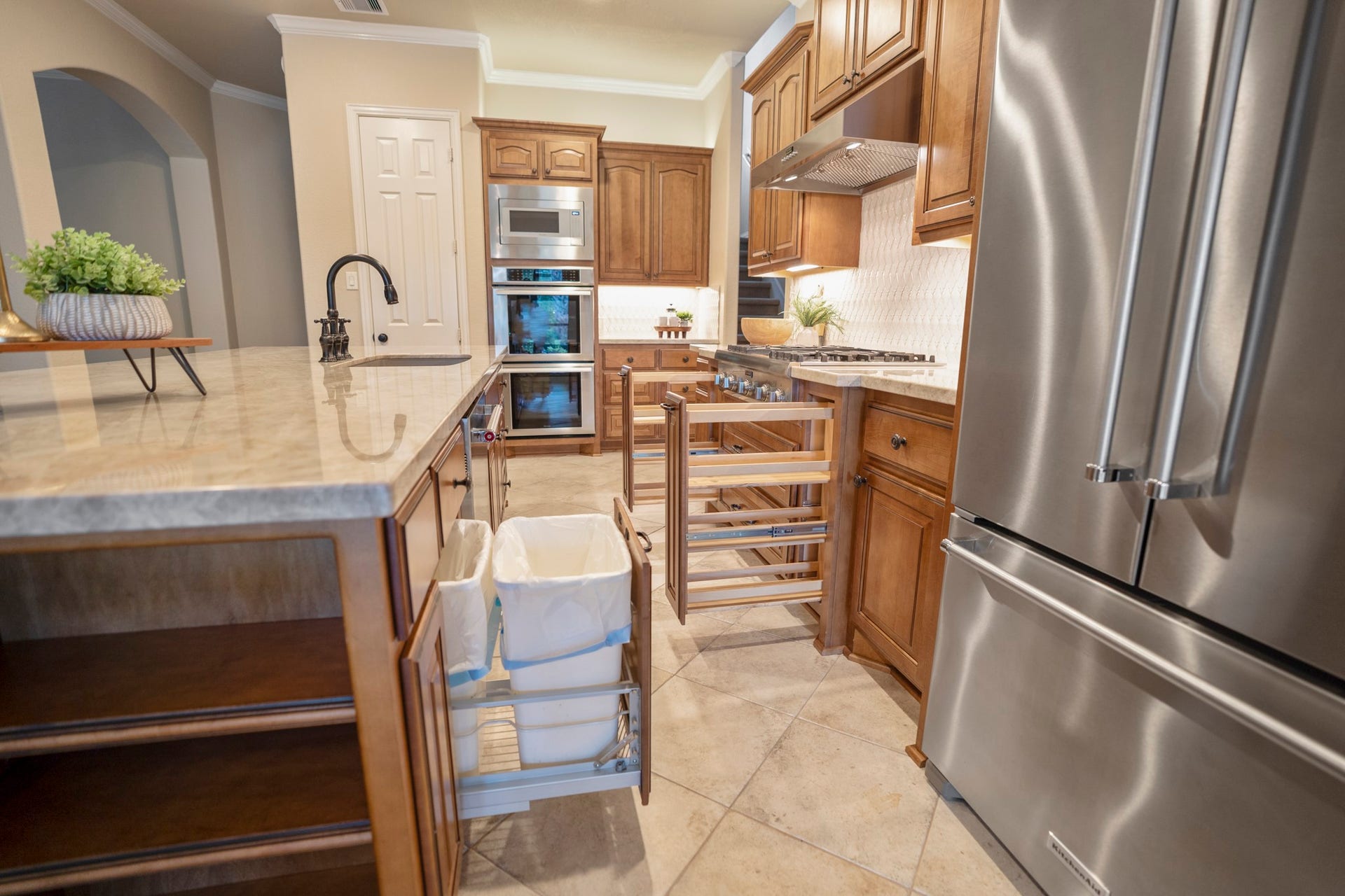 2407 Hendricks Lakes Drive, Spring, TX 77388 Turning back toward the cooking wall, the kitchen shows how thoughtfully the workspace is arranged with the island and seating to the left, stainless refrigerator to the right, and rich cabinetry wrapping the cooktop and built-in appliance area ahead.